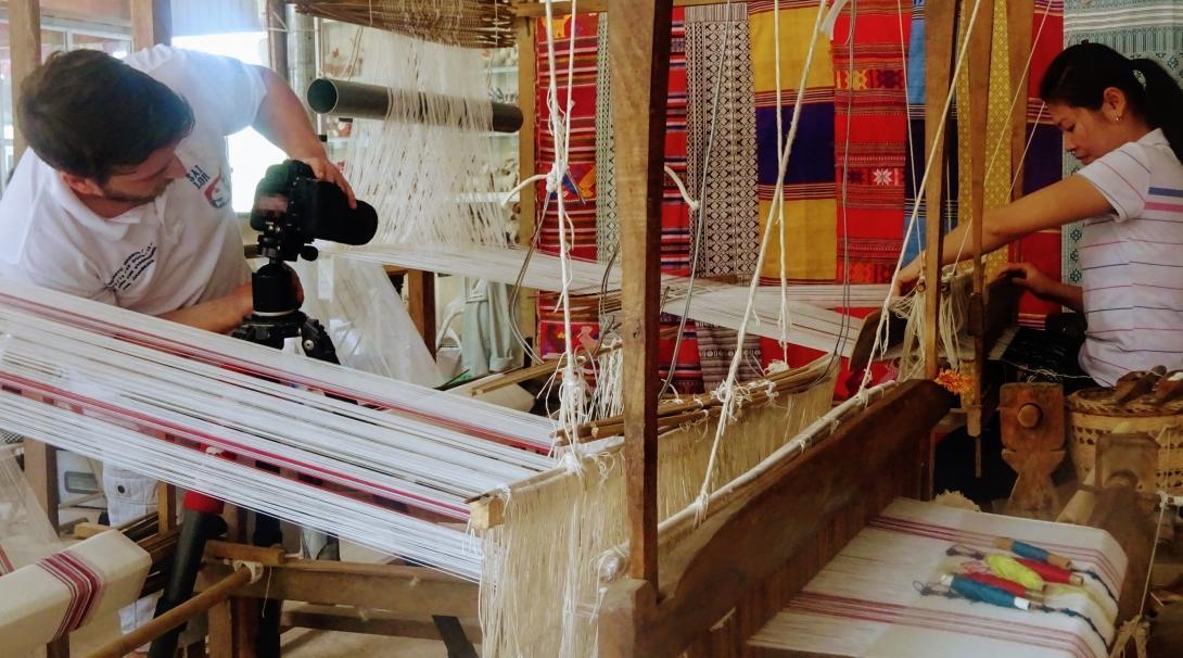 Male Projects Abroad Business intern photographs a local staff member weaving material during his Business Internship in Vietnam. Business intern photographs a female staff member weaving material for a product at a workshop in Vietnam.